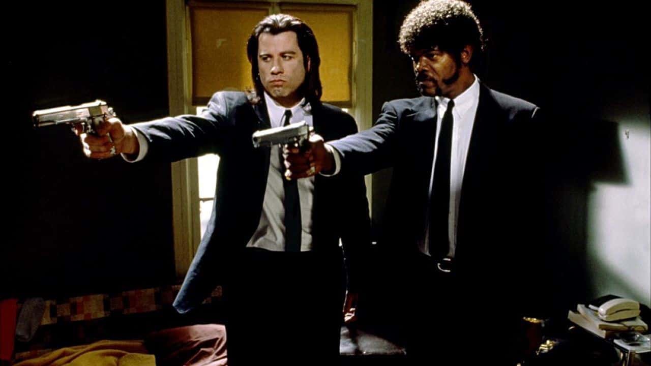Deux hommes en costume armés de fusils pointés l'un vers l'autre, une scène qui n'est pas sans rappeler l'intervention divine de Pulp Fiction.