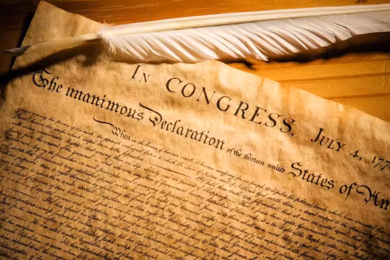 Declaration of Independence displayed beneath a quill, symbolising the political birth of the United States in 1776