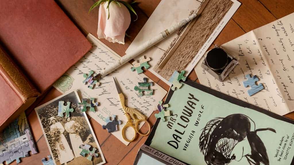 Une pile de papiers, de livres et de puzzles sur une table présentant la nouvelle technique de Virginia Woolf à travers le concept de temps.
