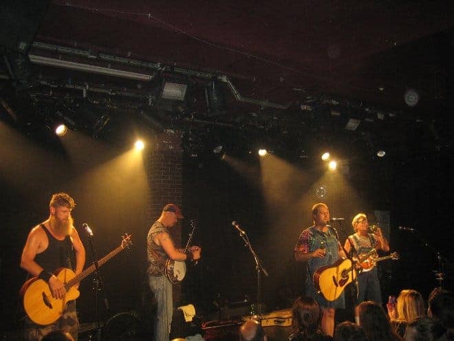 Hayseed Dixie donne un concert sur scène à la Maroquinerie avec guitares et batterie.